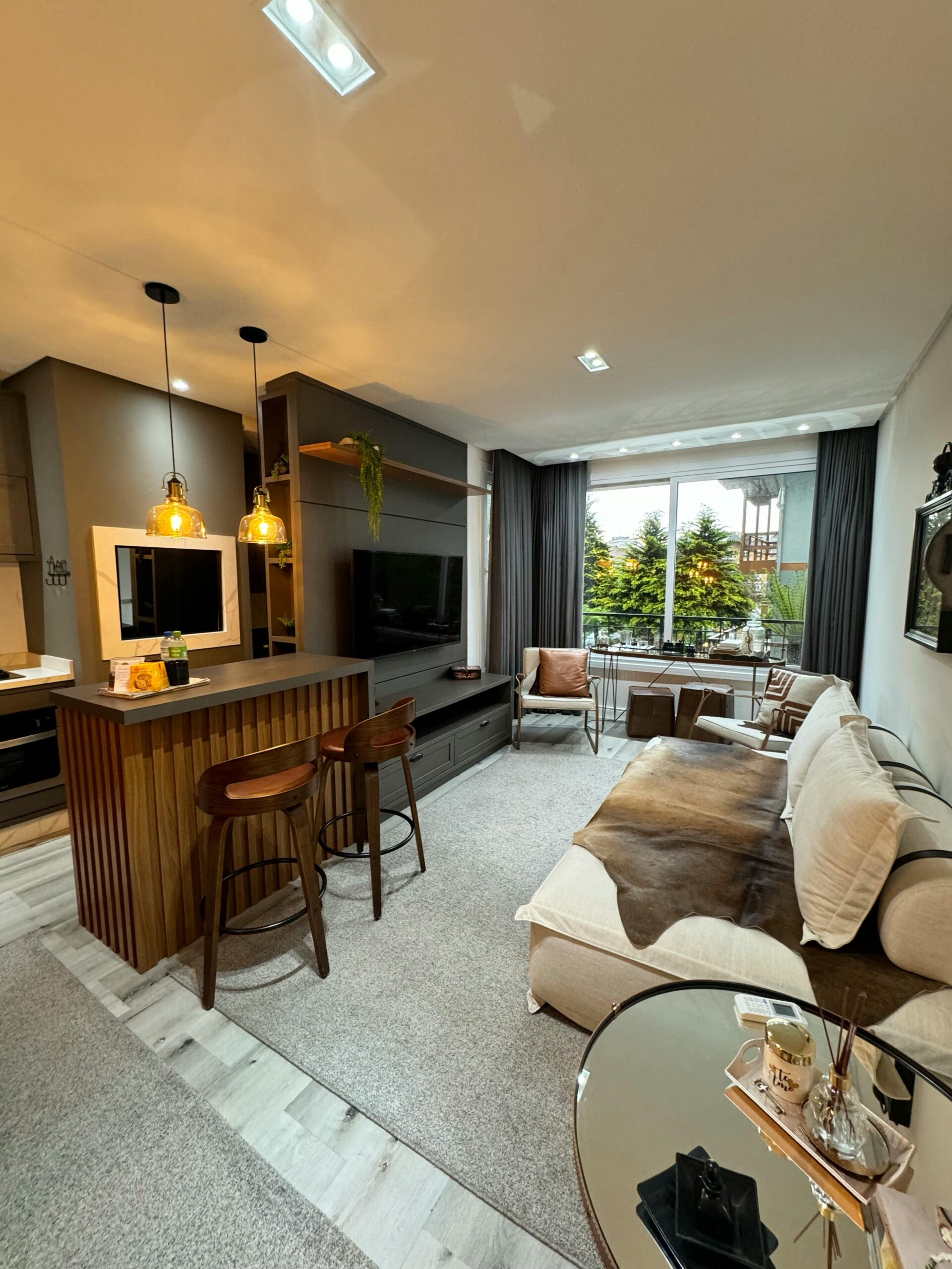Stylish modern living room with open kitchen, warm lighting, and chic decor.